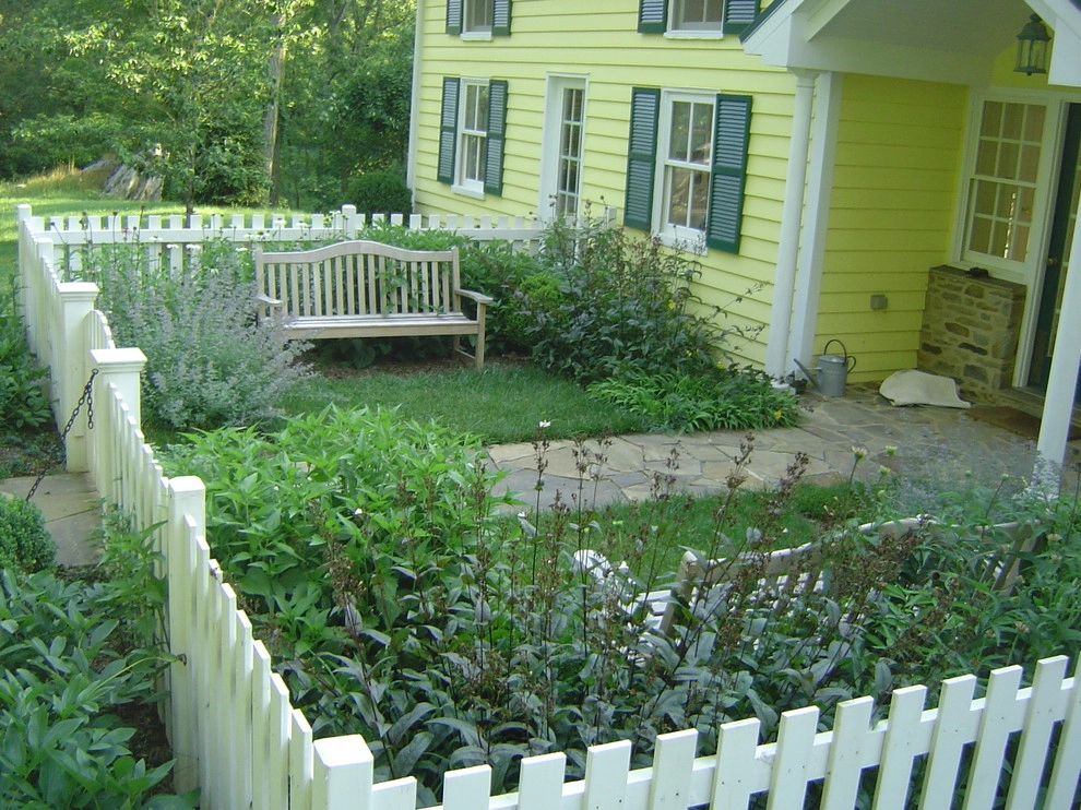 Fenced-in front yard with stone walkway and benches by Rock Water Farm - Photo 2