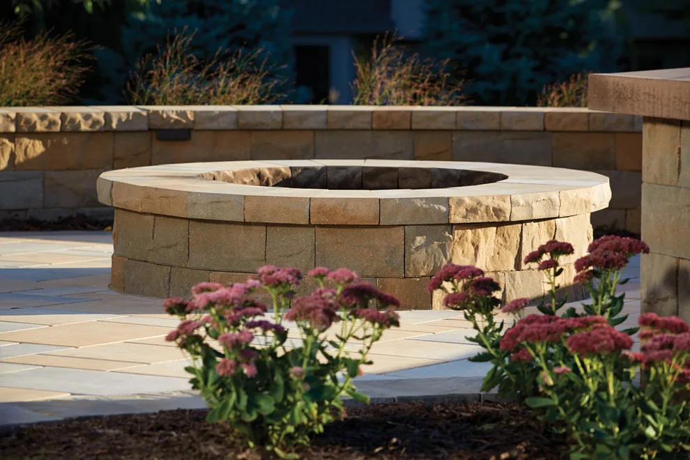 Charming Outdoor Space: Paver patio featuring a fire pit and seating wall by Anchor Block Company - Photo 2