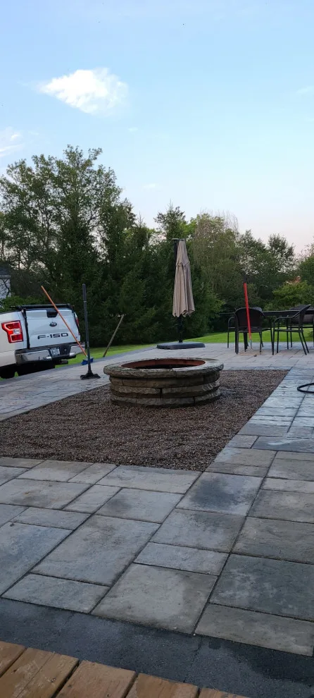 Elevated paver patio featuring stone steps and a fire pit by Legacy Masonry & Hardscaping - Photo 4