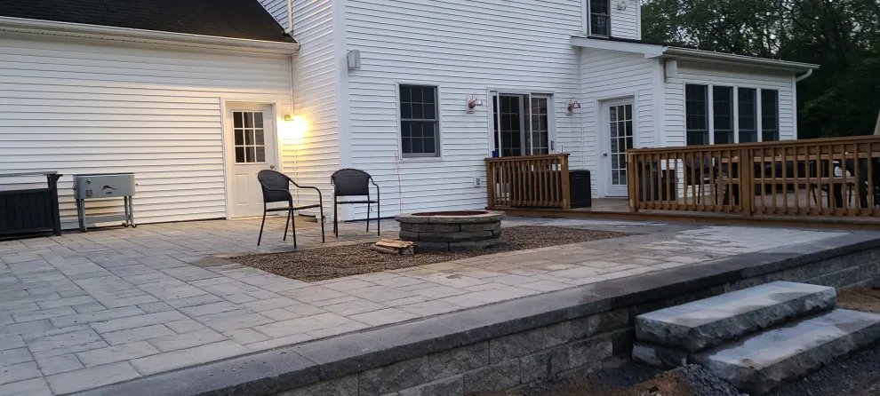 Elevated paver patio featuring stone steps and a fire pit by Legacy Masonry & Hardscaping - Photo 5