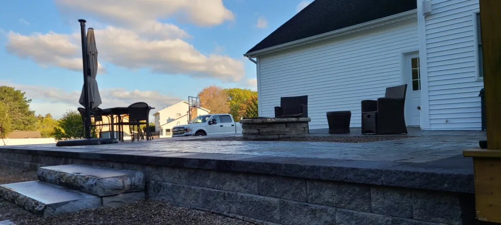Elevated paver patio featuring stone steps and a fire pit by Legacy Masonry & Hardscaping - Photo 3