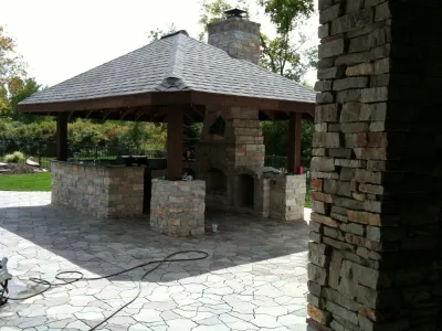 Outdoor Kitchen with fireplace by the pool — Landscape Construction project by Apex Landscape And Brick Services LLC in Canton