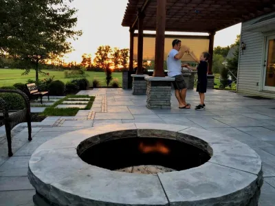 Outdoor living space with a pergola, fire pit, and grill with counter space — Landscape Construction project by Brick & Bloom Inc.