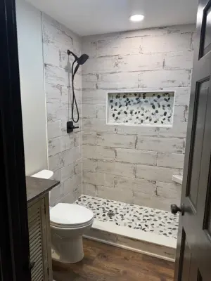 Farmhouse-Inspired Bathroom Renovation Featuring Wood-Effect Tiles and Pebble Shower Flooring — Home Renovation & Remodeling Services project by Big League Builders And Remodelers