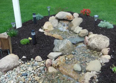 Smalley Pondless Waterfall, fountainscape, mulch, edging and plants — Landscape Construction project by Premiere Aquascapes