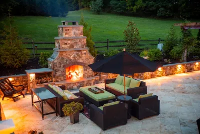 Infinity edge swimming pool, fireplace and travertine patio. by Rock Water Farm