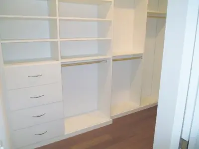 Minimalist and pristine white walk-in wardrobe by Closet Solutions