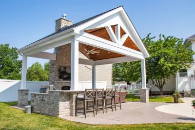 Gabled Pool House Featuring a Fireplace and Grilling Space by Heartlands Building Company