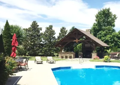 Outdoor Kitchen and Fireplace by the Pool in Alabama by Homestead Timber Frames