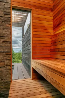 Charming outdoor wood-fired sauna with a deck, covered space, and custom features — Design-Build Services project by Treeline Construction